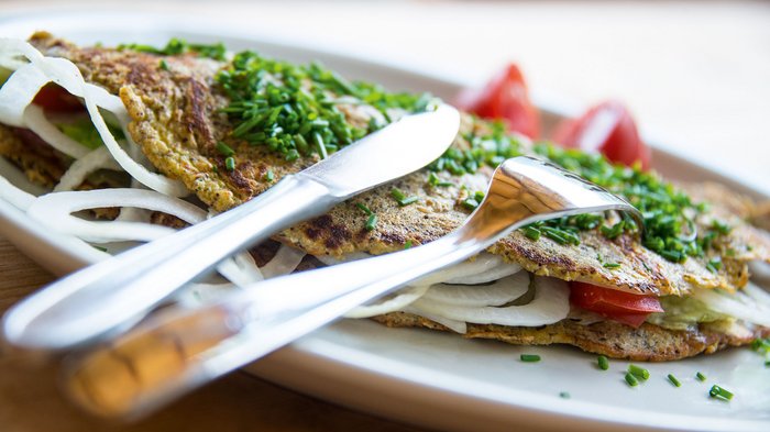 Discover the Alpine huts in Meransen, Vals & Co. An omelette filled with onions and tomatoes, sprinkled with fresh chives.